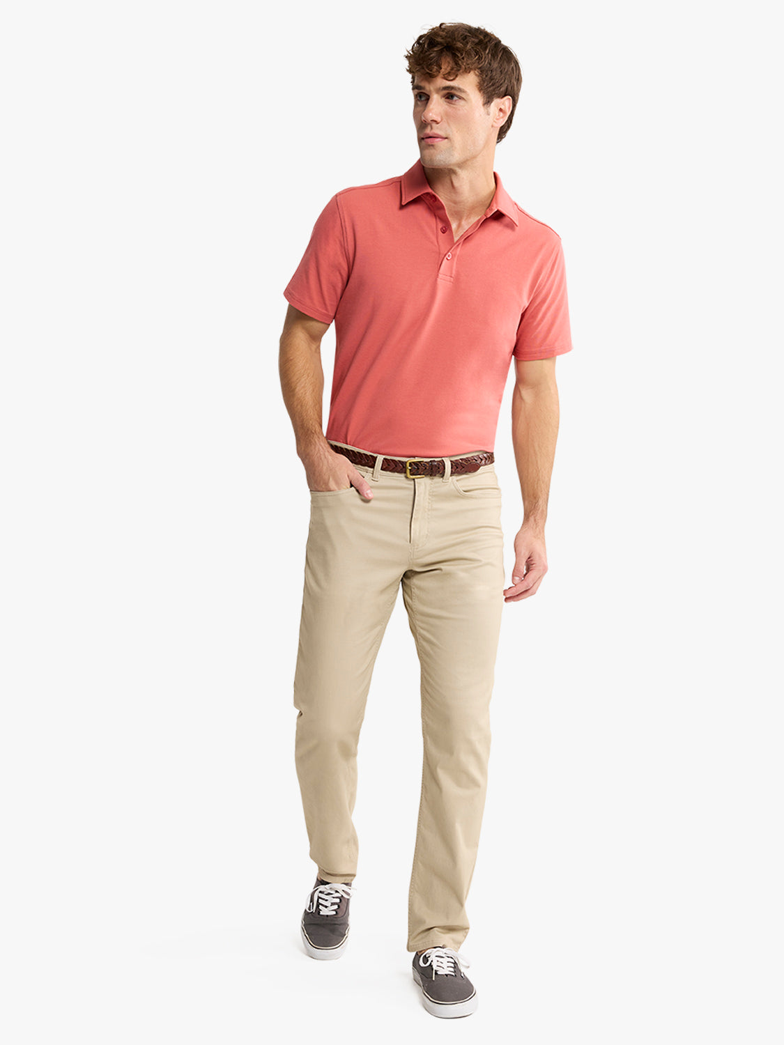 Man wearing a coral polo shirt and khaki five-pocket pants with a brown belt.