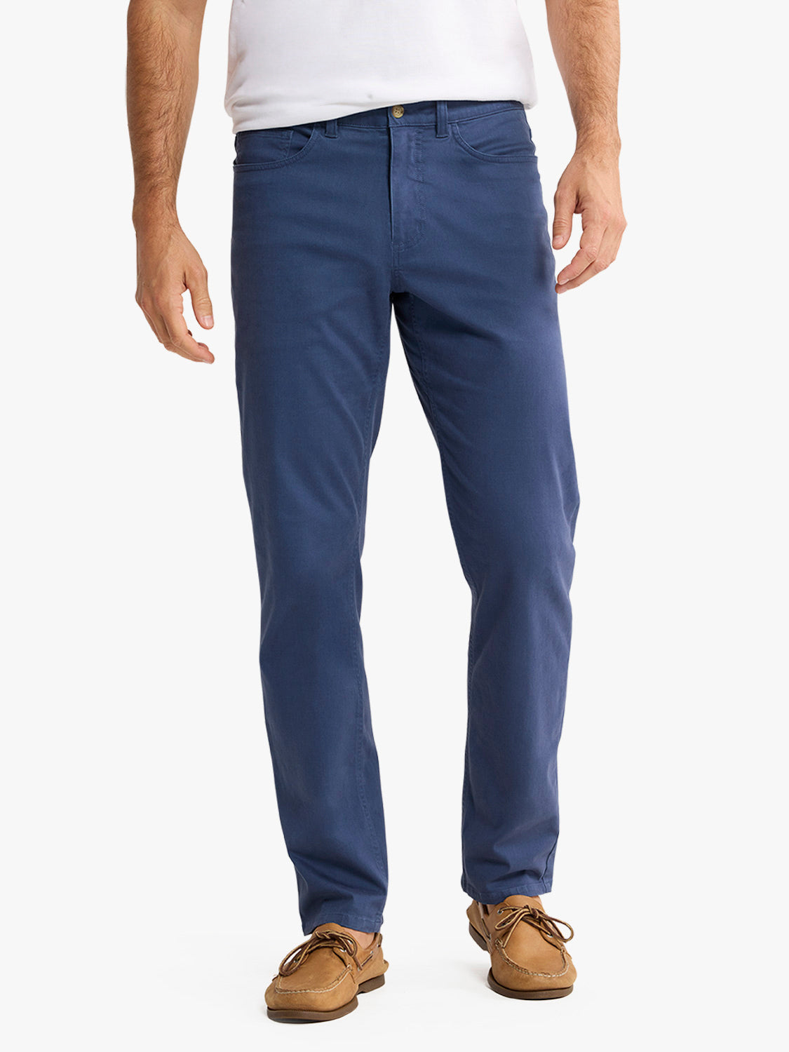 Man wearing navy five-pocket pants with a white t-shirt and tan boat shoes.
