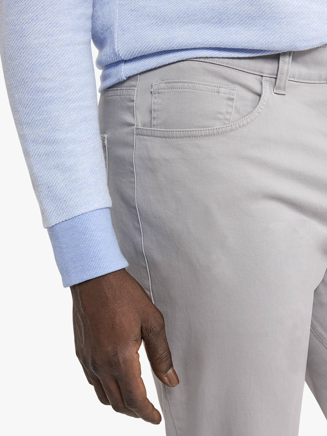 Light gray five-pocket pants with visible waistband and front pocket details worn with blue shirt.