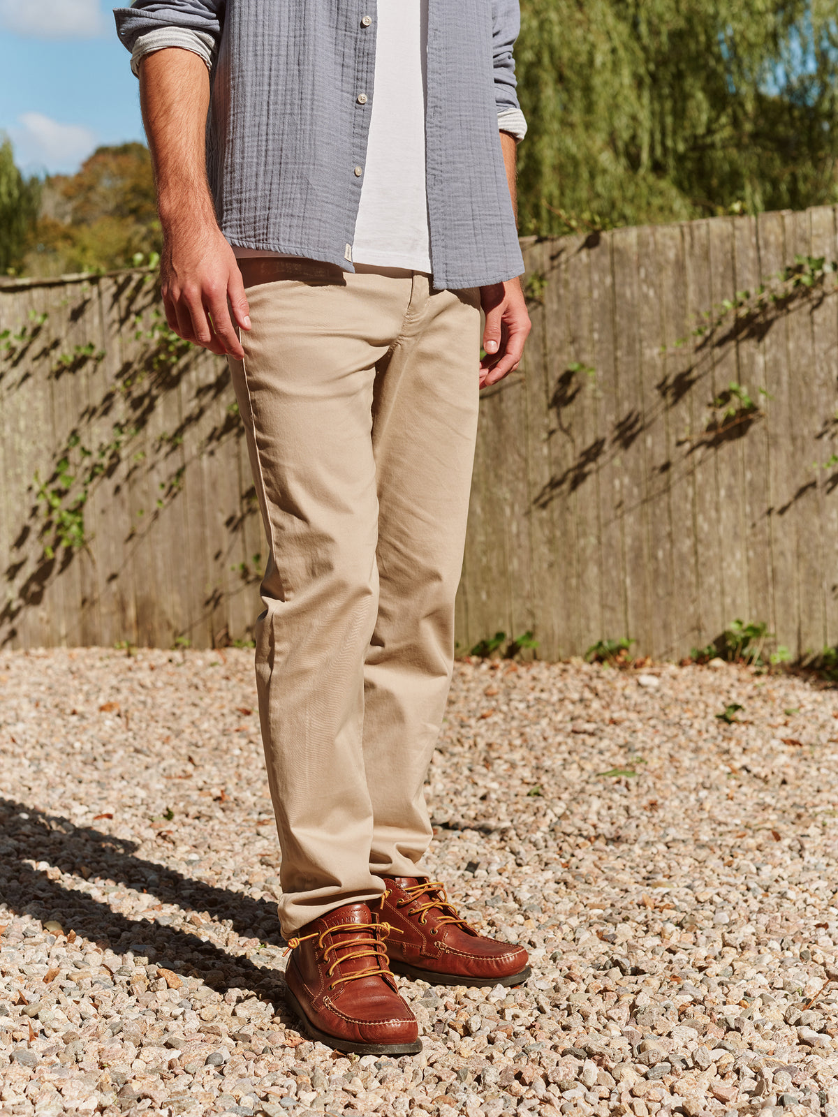 Man wearing khaki five-pocket pants with a gray button-up shirt and brown leather boots.