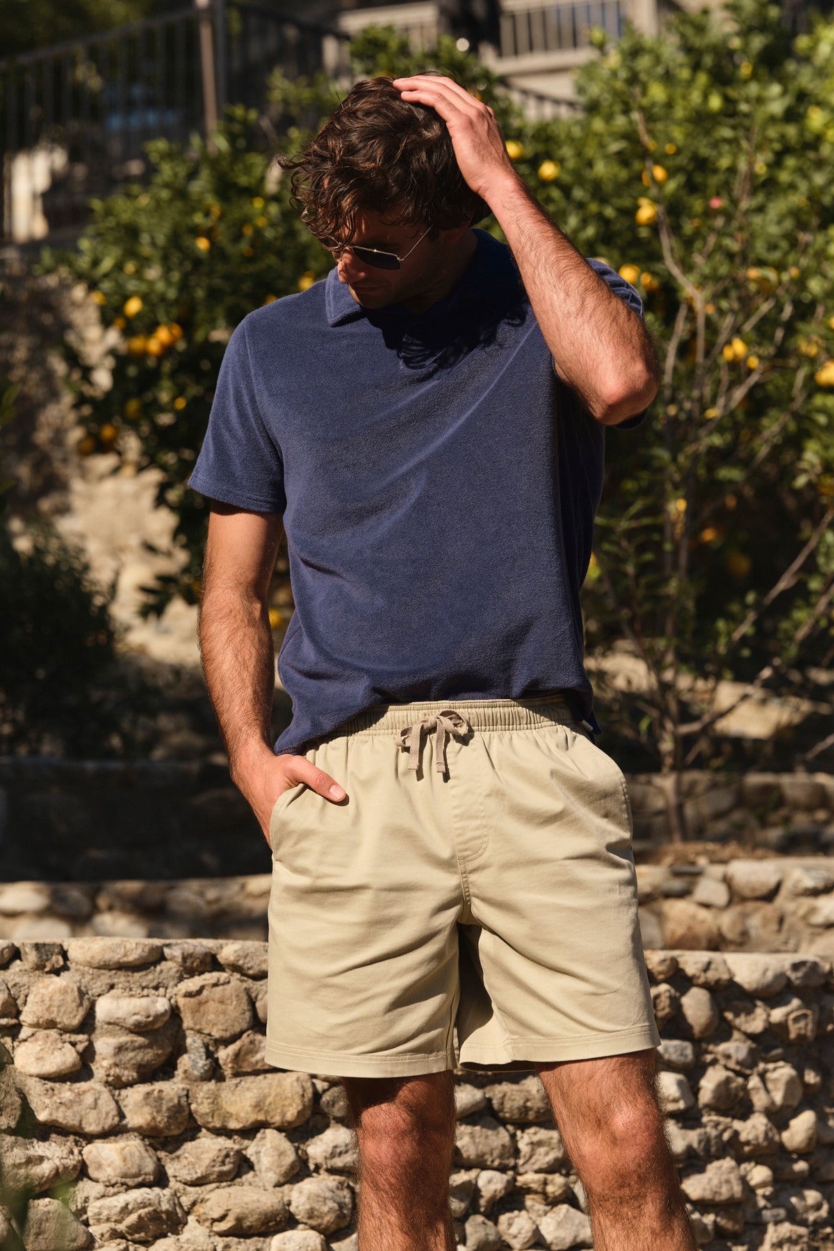 Man wearing khaki pull-on shorts with an elastic waistband and drawstring, styled with a navy polo shirt.