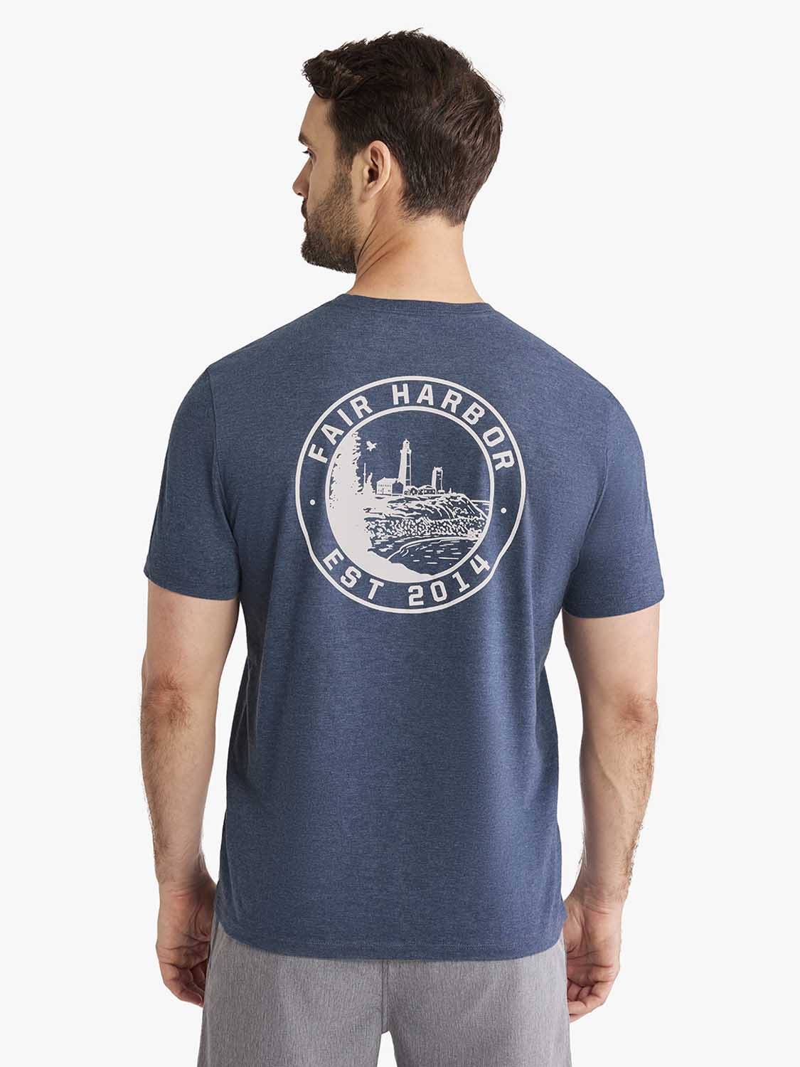 Man wearing a blue-gray t-shirt with a circular lighthouse graphic and text on the back.