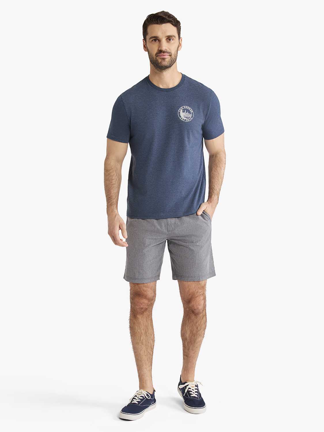 Man wearing a blue graphic tee with a lighthouse stamp design on the chest.
