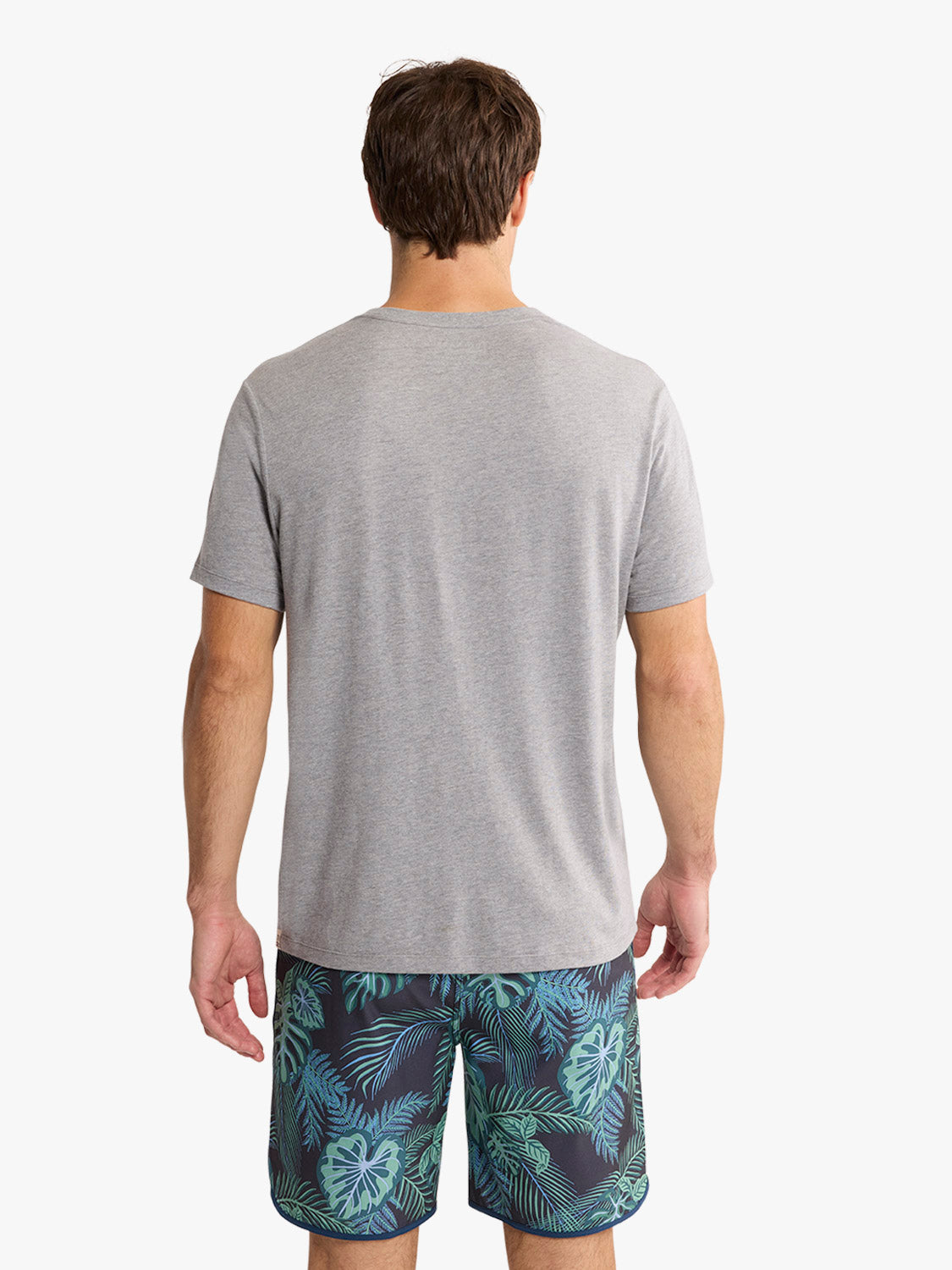 Man wearing heather grey short-sleeve t-shirt and tropical print shorts, shown from behind.