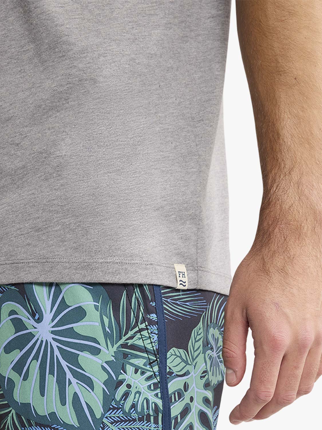 Heather grey t-shirt with crew neckline worn with patterned swim shorts.