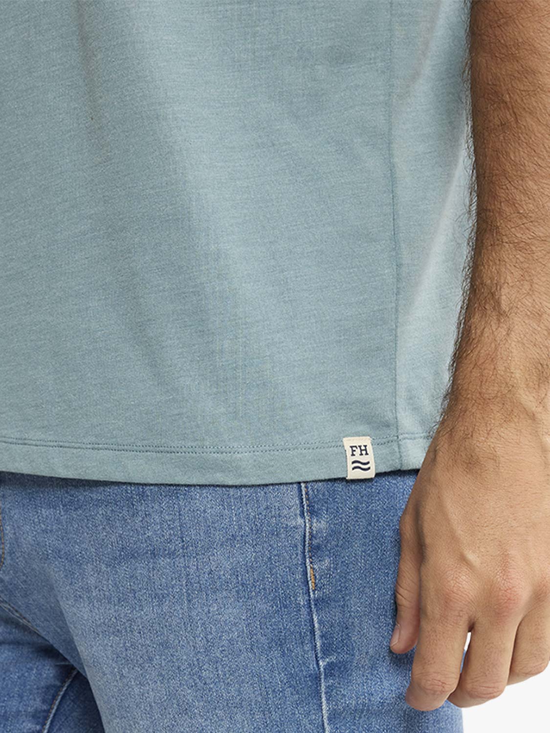 Heather green t-shirt worn by a man paired with blue jeans, showing the side fit.