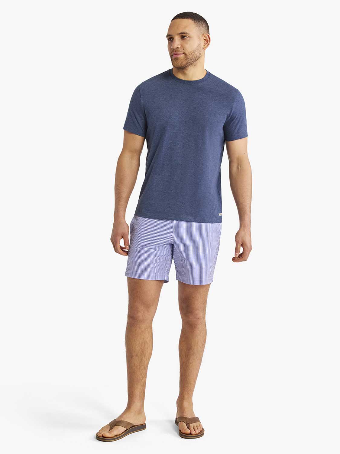 Man wearing a navy heathered crew neck t-shirt with short sleeves and lavender shorts.