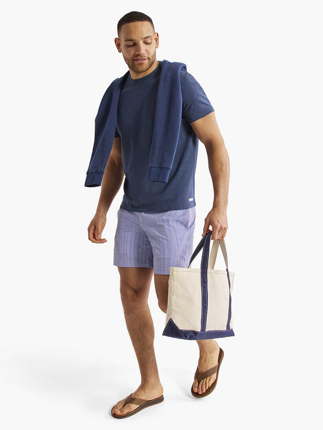 Man wearing navy short-sleeve tee with matching cardigan and light purple striped shorts.
