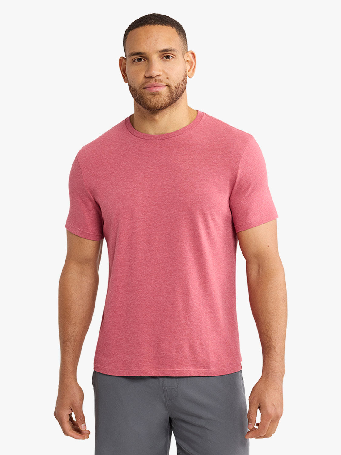 Man wearing a red heathered crew neck t-shirt with short sleeves and gray shorts.