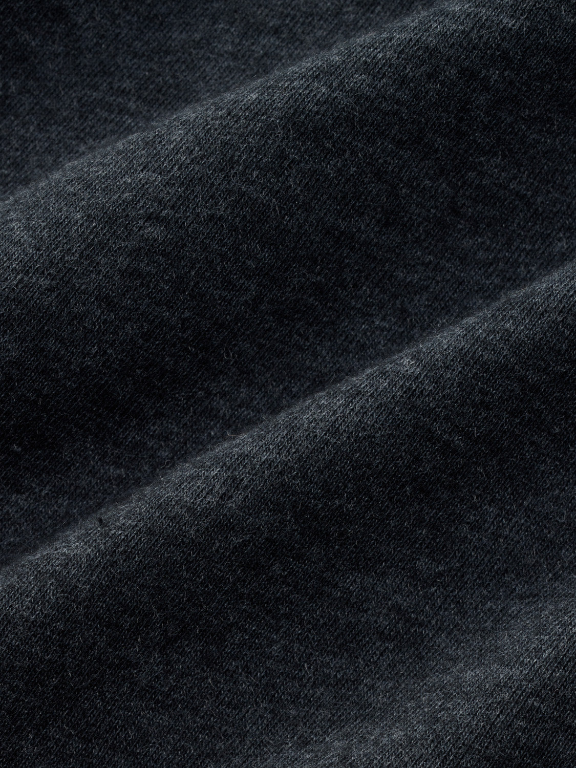 Close-up of black textured fabric showing diagonal folds and knit weave detail.