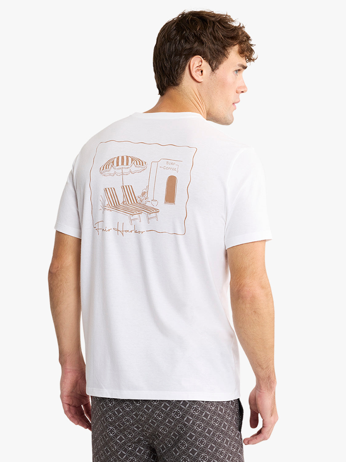 White short-sleeve t-shirt with a tan line drawing on the back depicting a beach cafe scene with umbrella and lounge chair.