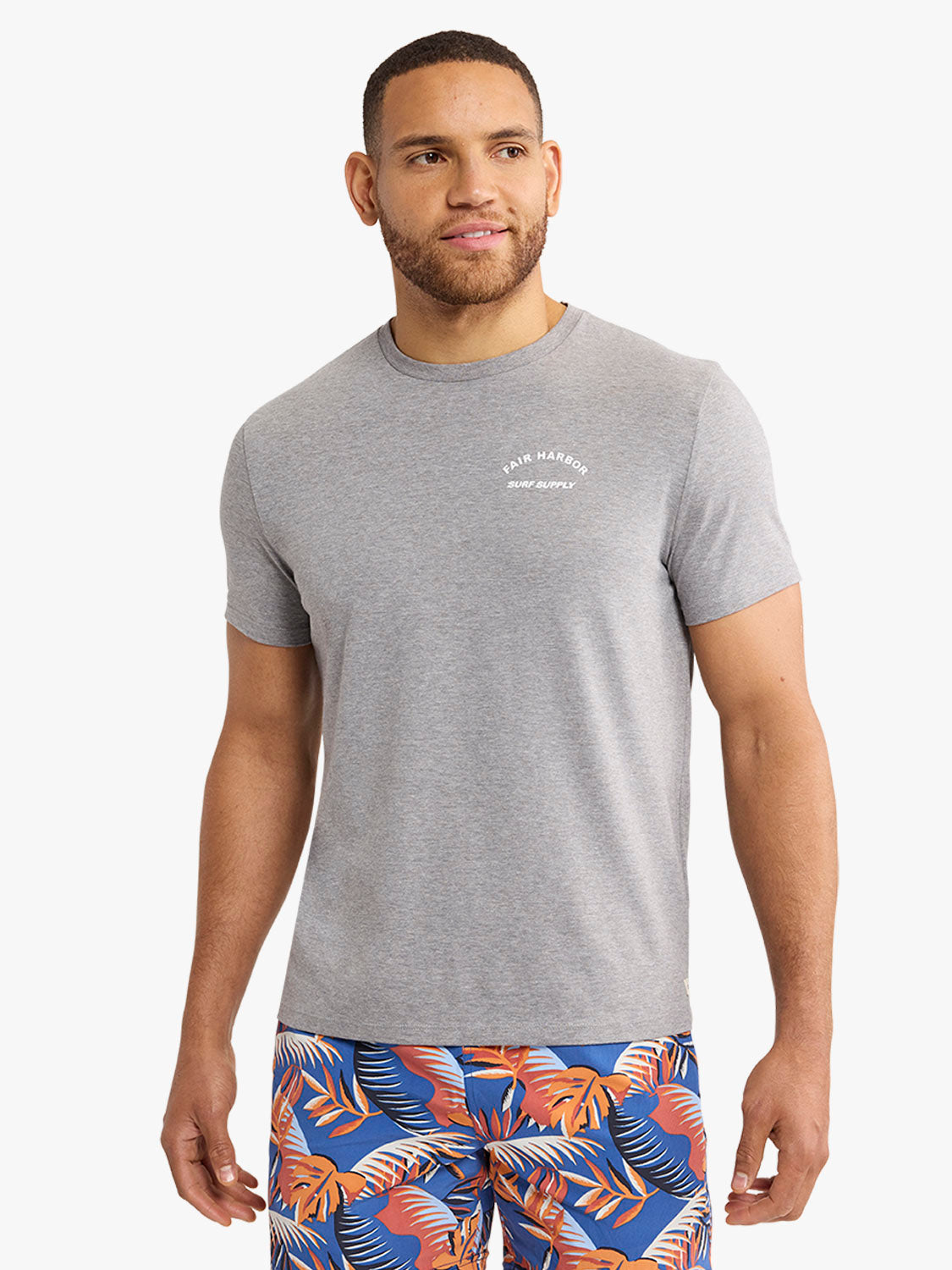 Man wearing a gray crew neck t-shirt with Fair Harbor Surf Supply text graphic on chest.