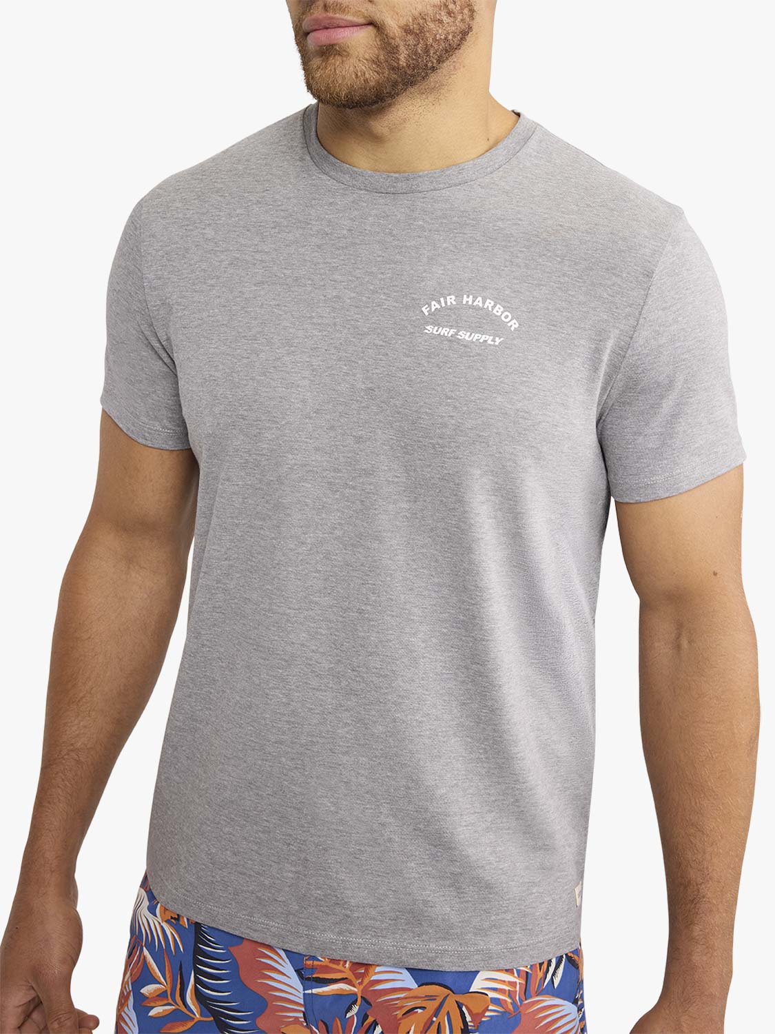 Man wearing a gray crewneck t-shirt with Fair Harbor Surf Supply text printed on chest.