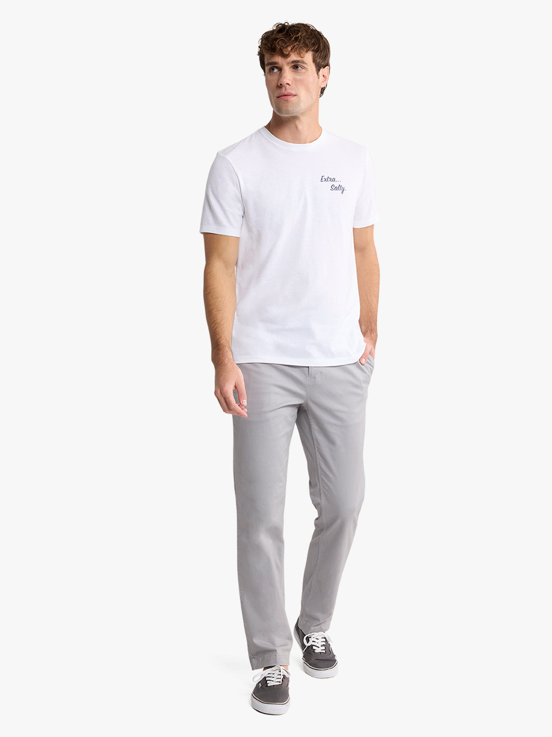 Man wearing a white short-sleeve graphic tee with small chest text and light gray pants.