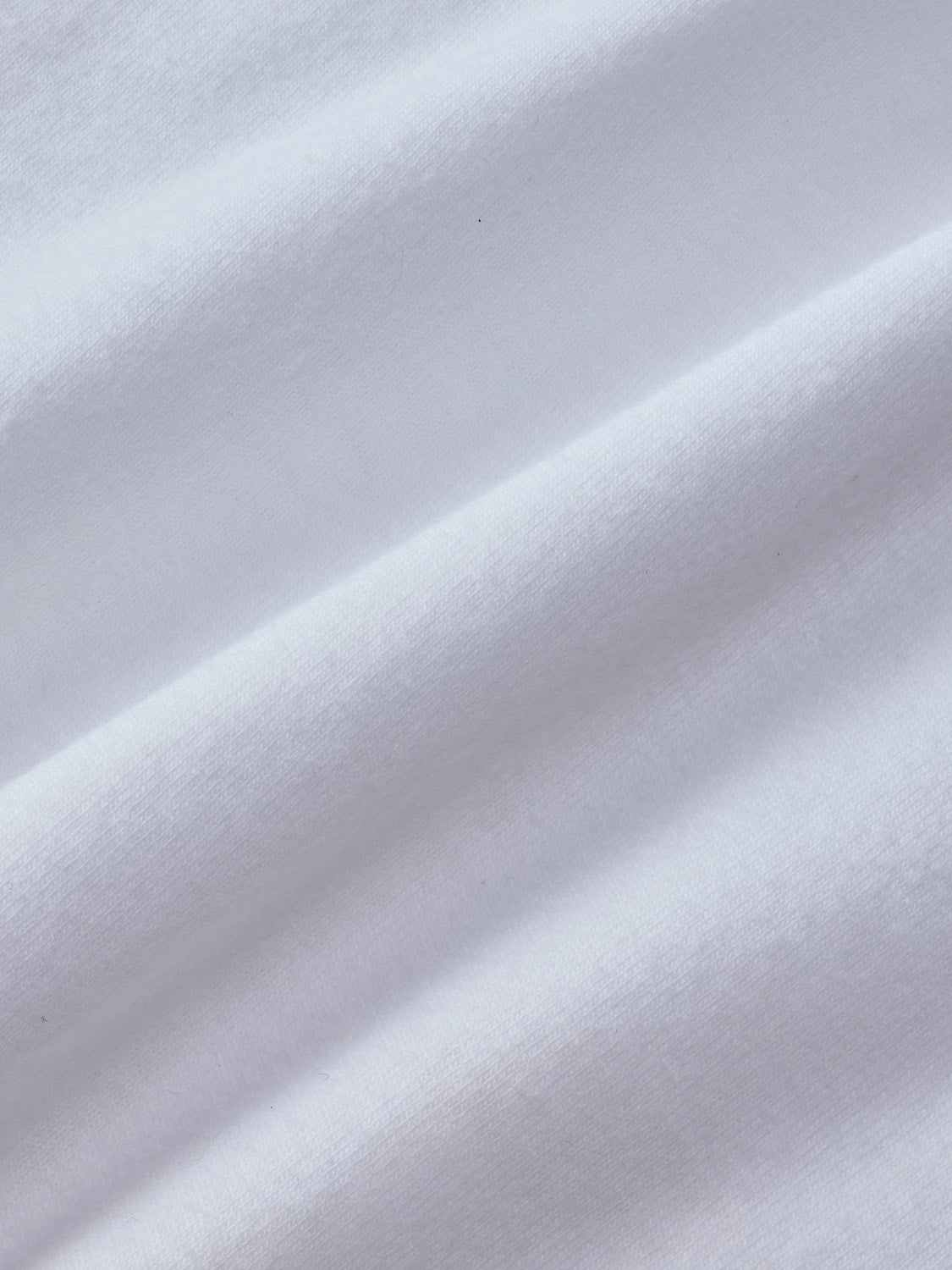 White cotton graphic tee with textured fabric and diagonal folds throughout the garment.