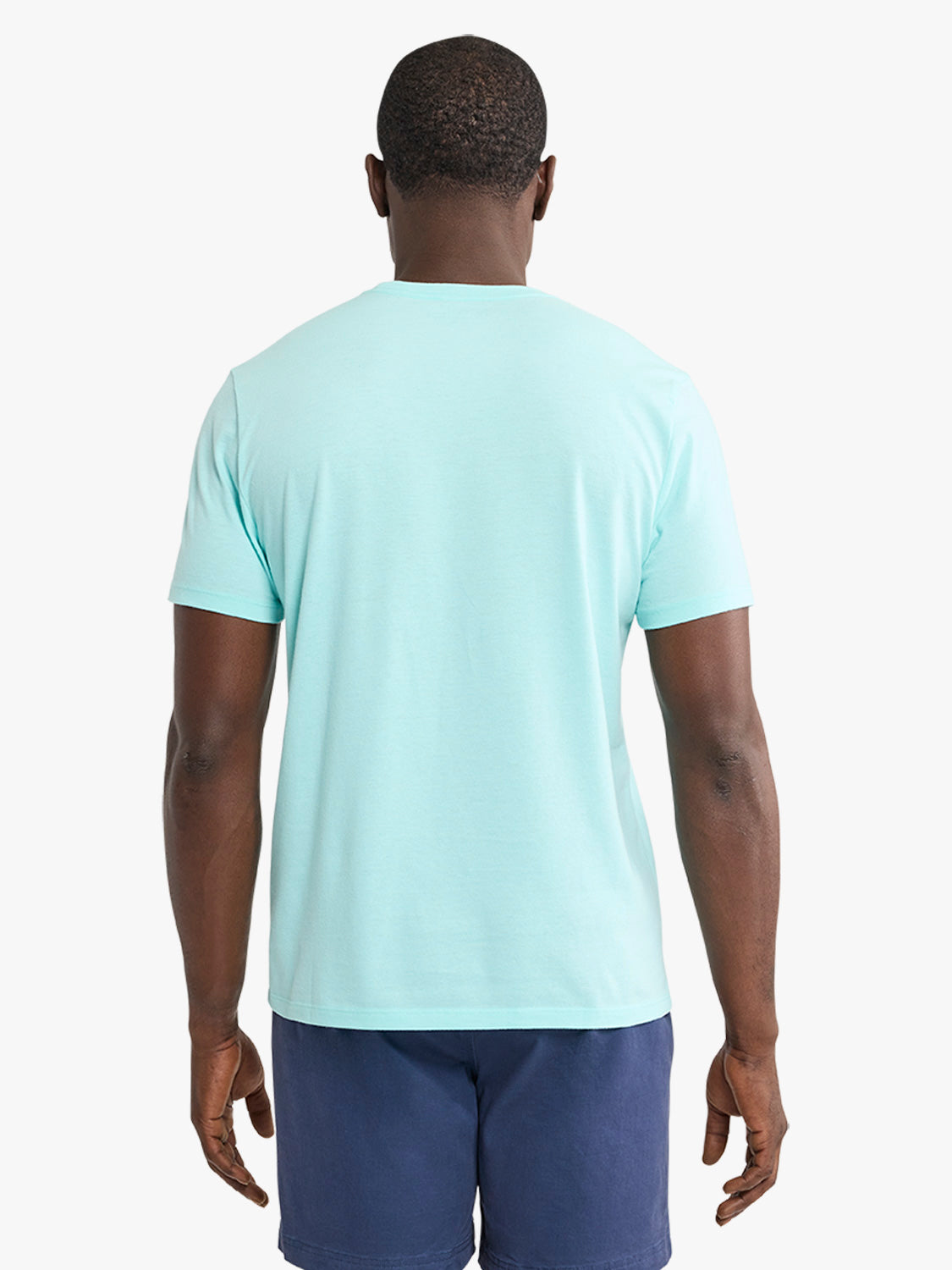 Man wearing an aqua short-sleeve t-shirt and navy shorts, shown from behind.
