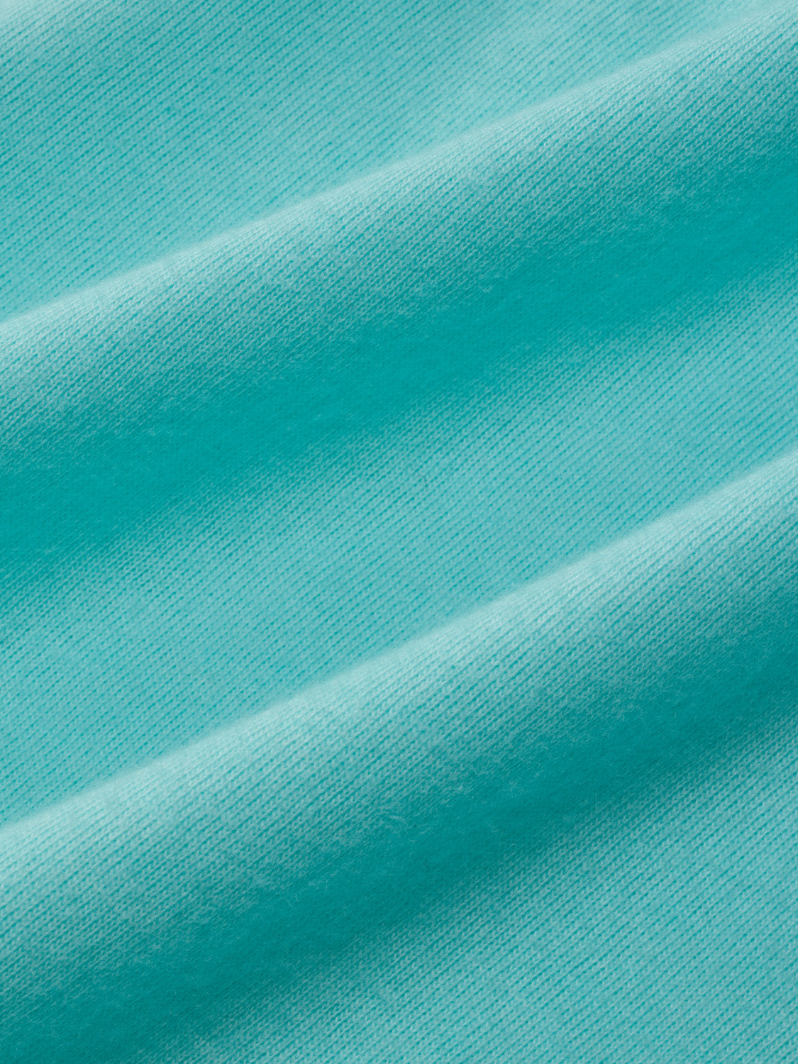 Aqua-colored ribbed fabric with diagonal folds and shadows creating texture and depth.