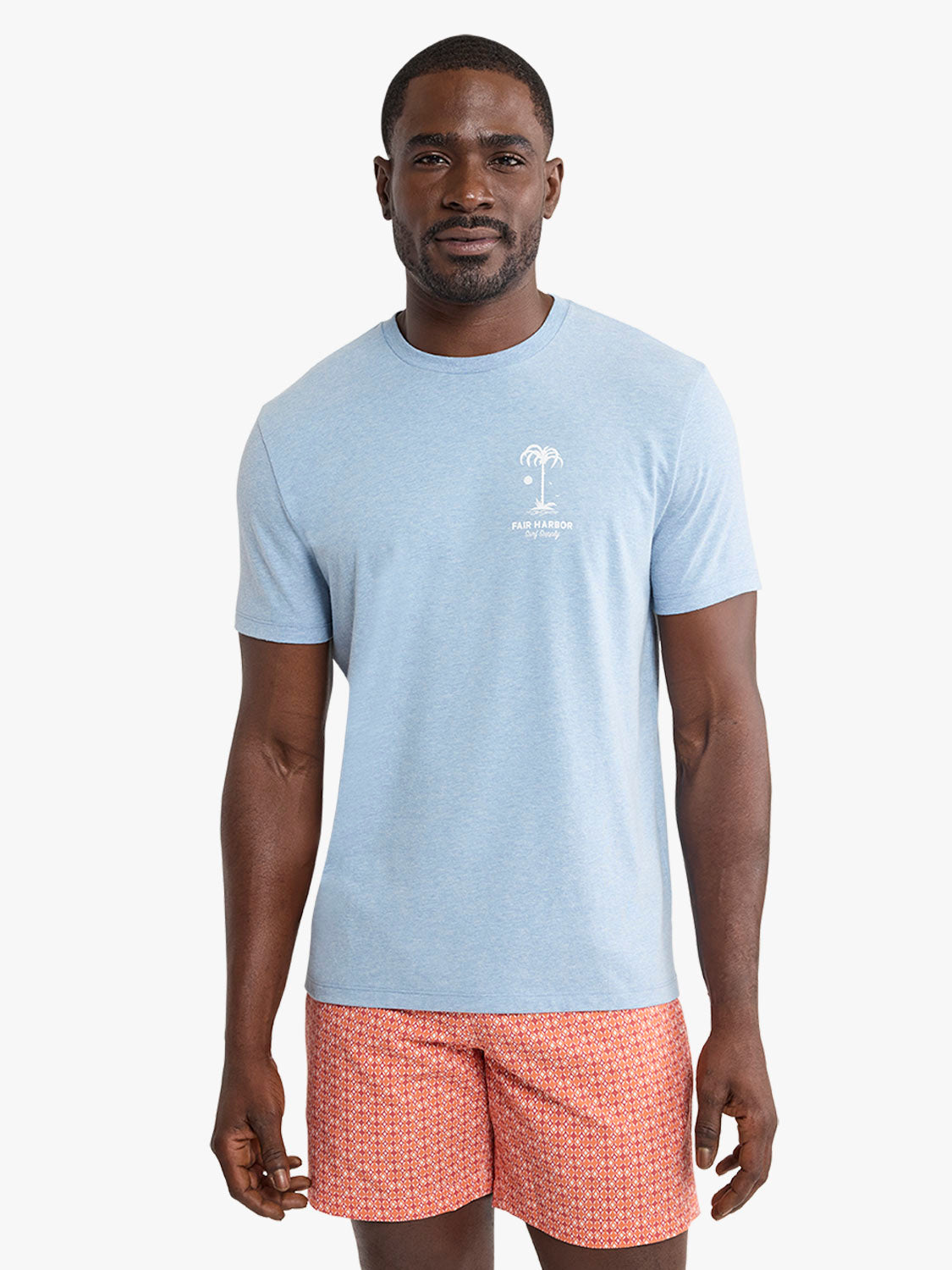 Man wearing a light blue graphic tee with a palm tree design and Fair Harbor text.