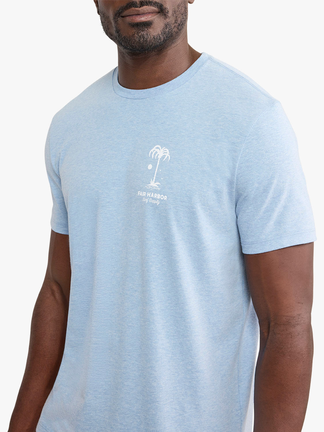 Man wearing a light blue graphic t-shirt with a white palm tree and 