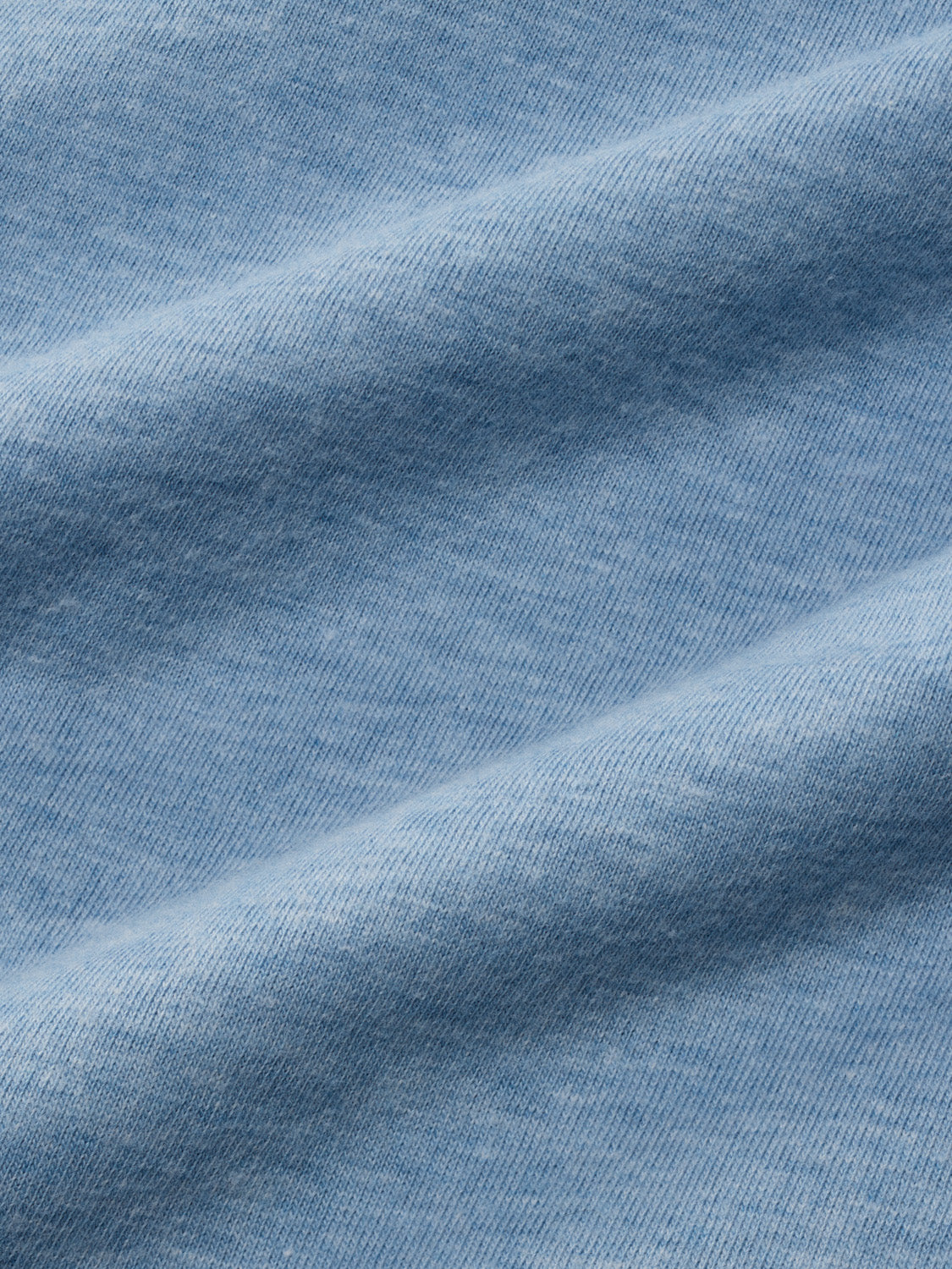 Medium blue heathered cotton t-shirt fabric with ribbed texture and diagonal fold shadows.