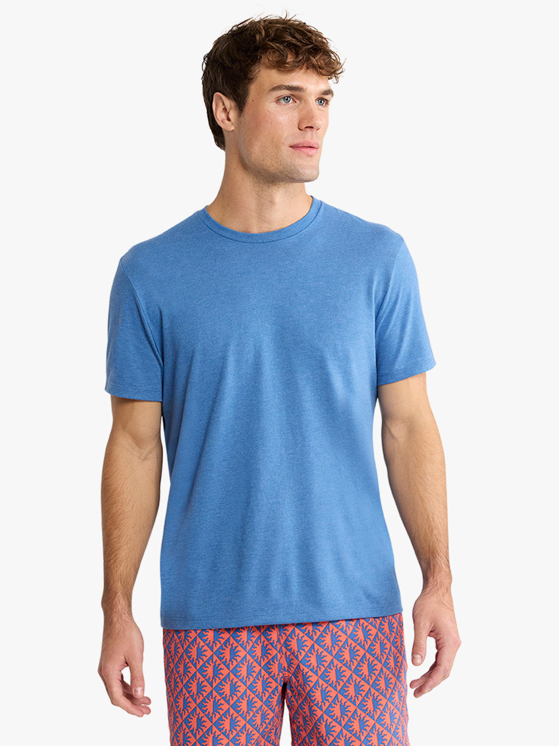 Man wearing a sea blue short-sleeve crewneck tee shirt with geometric patterned shorts.