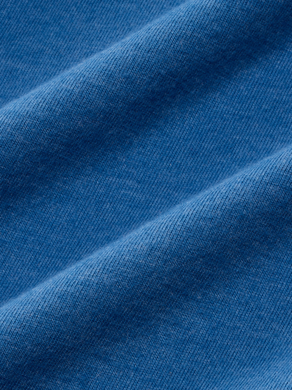 Sea blue ribbed knit fabric with diagonal folds and texture detail visible.