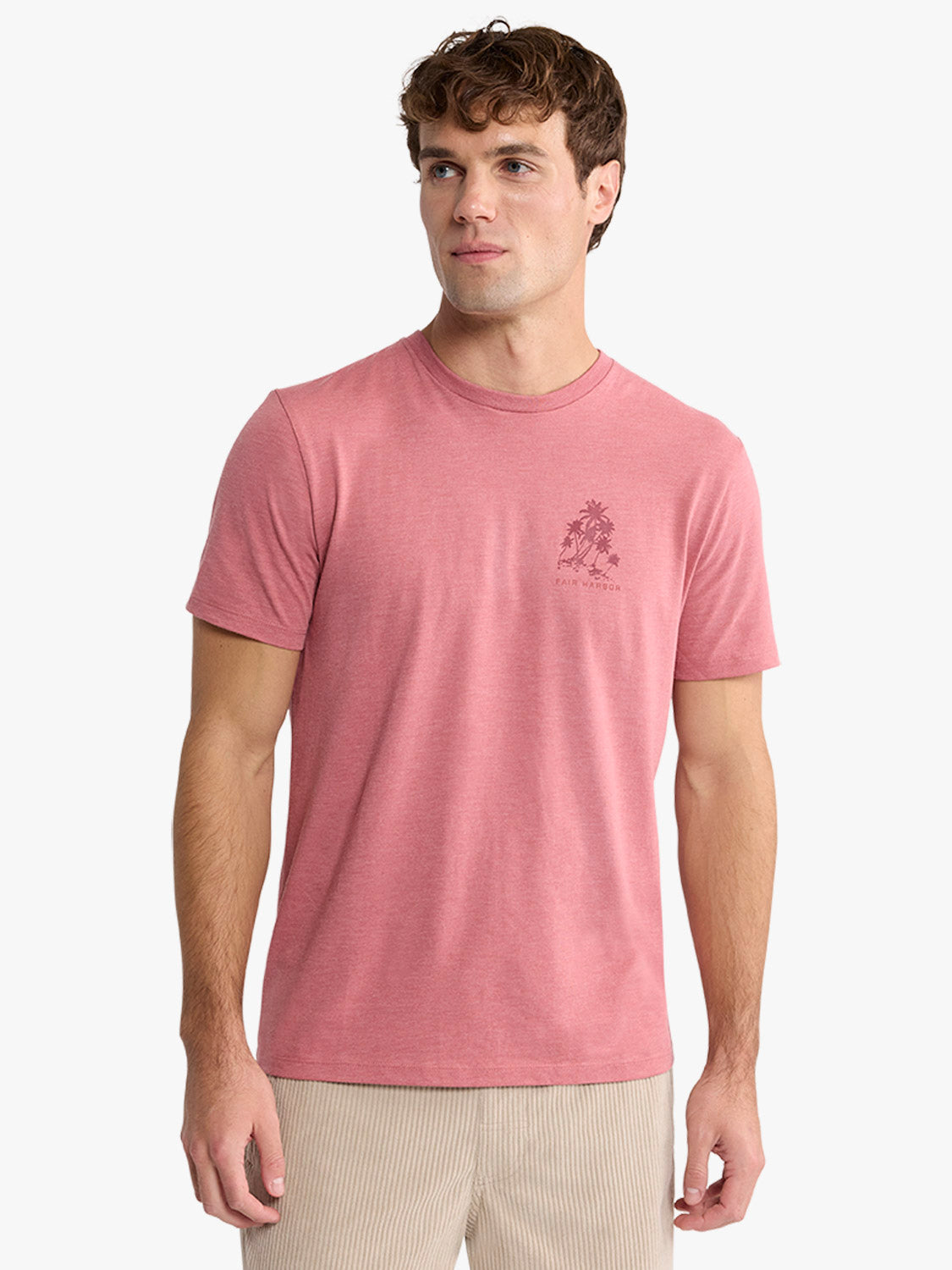 Man wearing a pink short-sleeve crew neck tee with a small palm tree graphic on the chest.