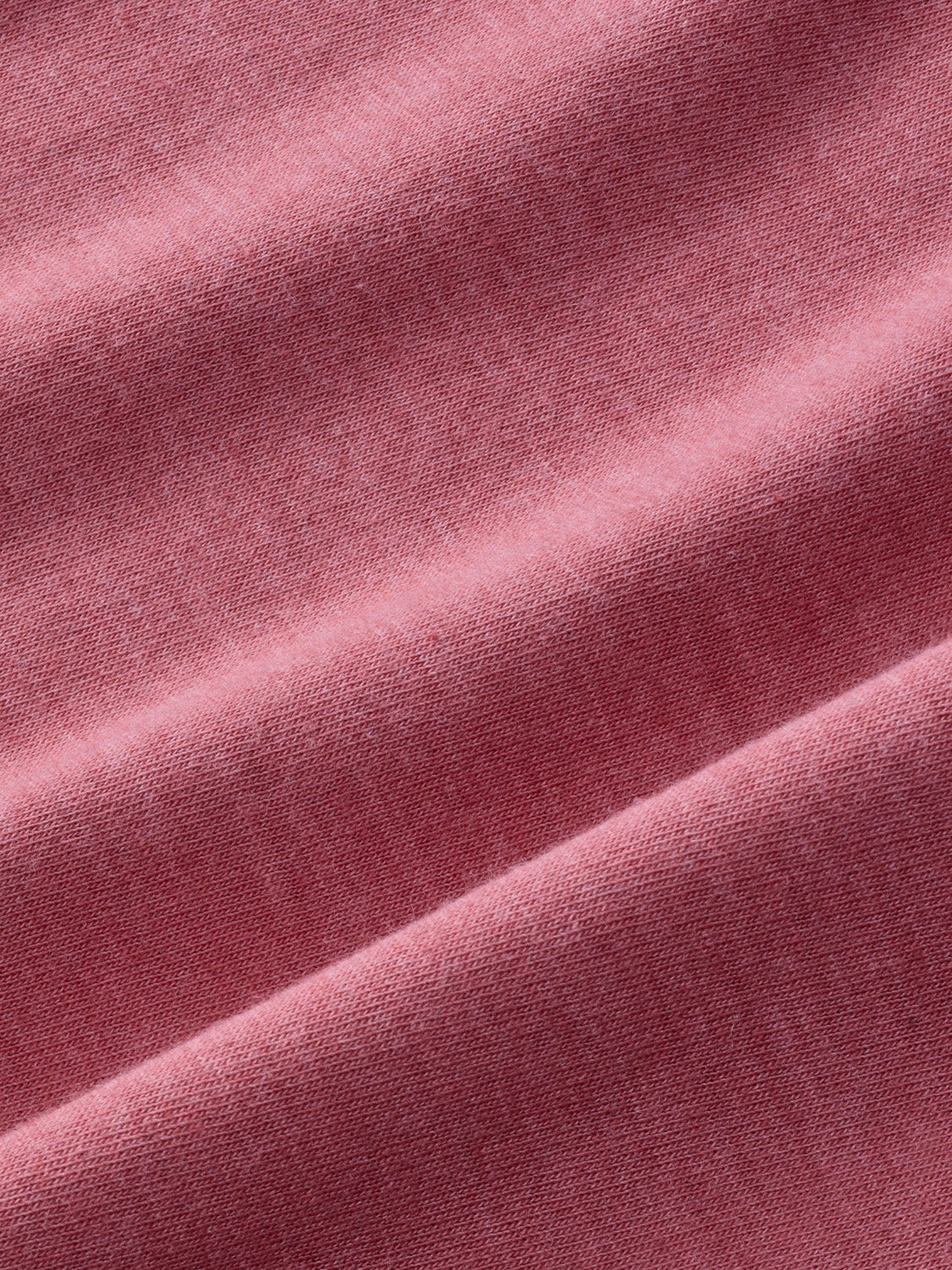 Close-up of dusty rose pink fabric with textured weave and subtle color variations throughout.