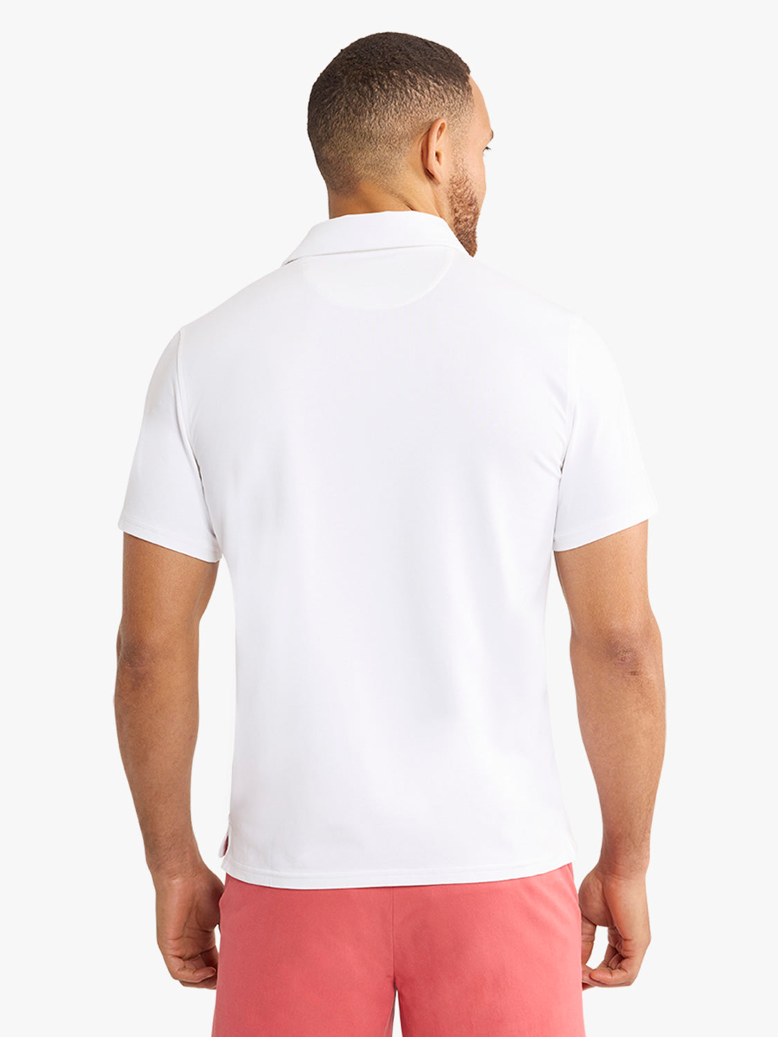 Man wearing a white polo shirt with a collared neckline and short sleeves, shown from behind.