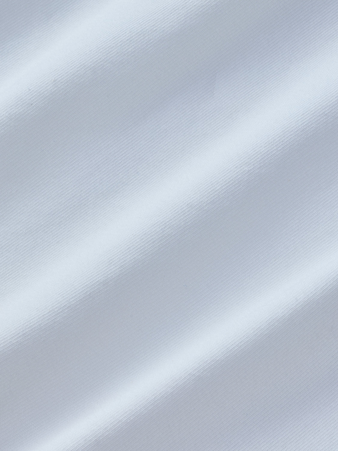 White polo shirt with textured fabric showing diagonal ribbed pattern and natural light reflections.