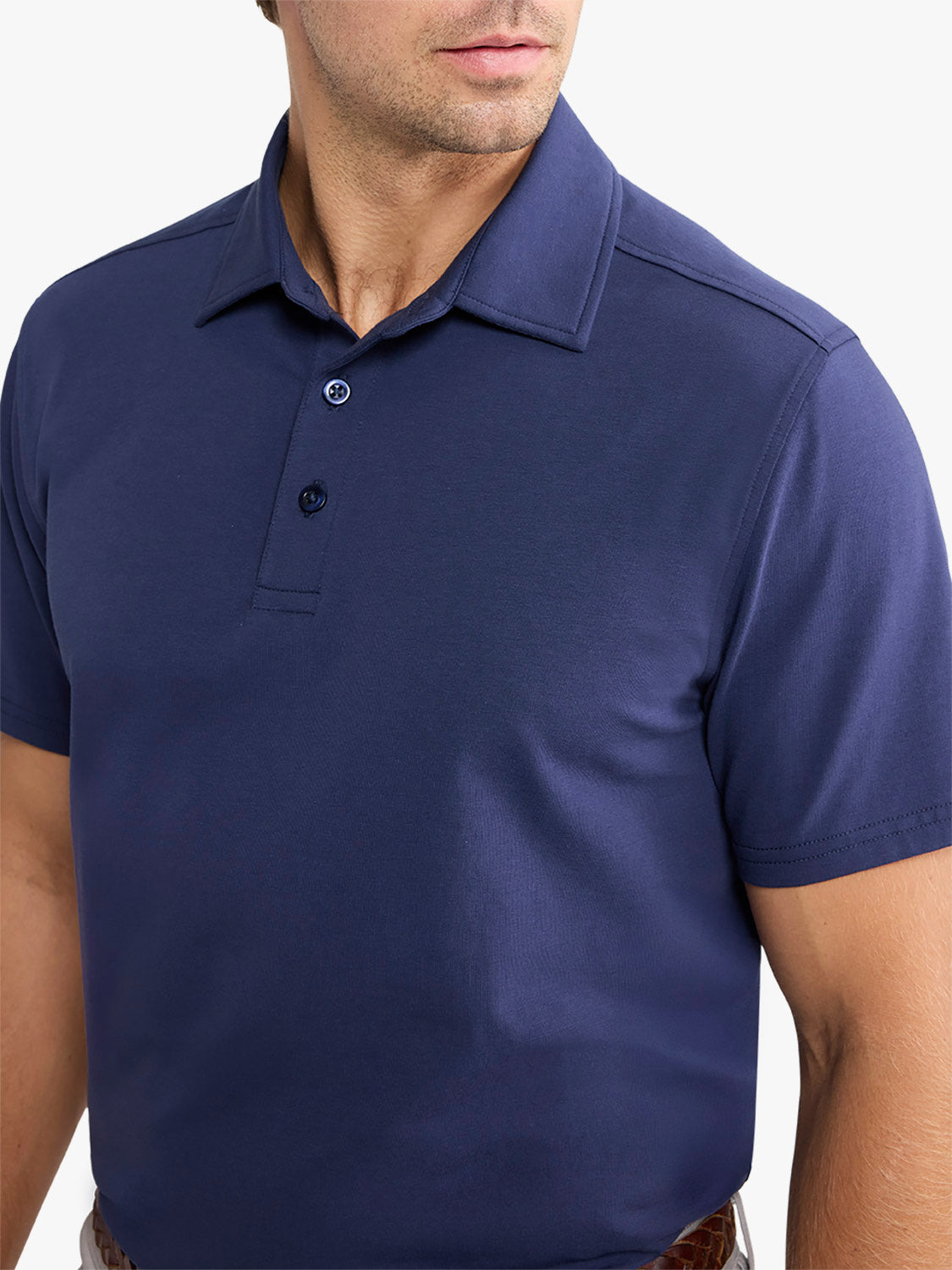 Man wearing a navy short-sleeved polo shirt with a collared neckline and button front closure.