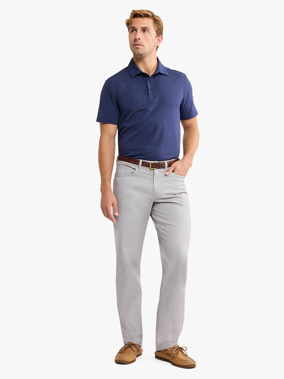 Man wearing a navy short-sleeve polo shirt with light gray pants and a brown leather belt.
