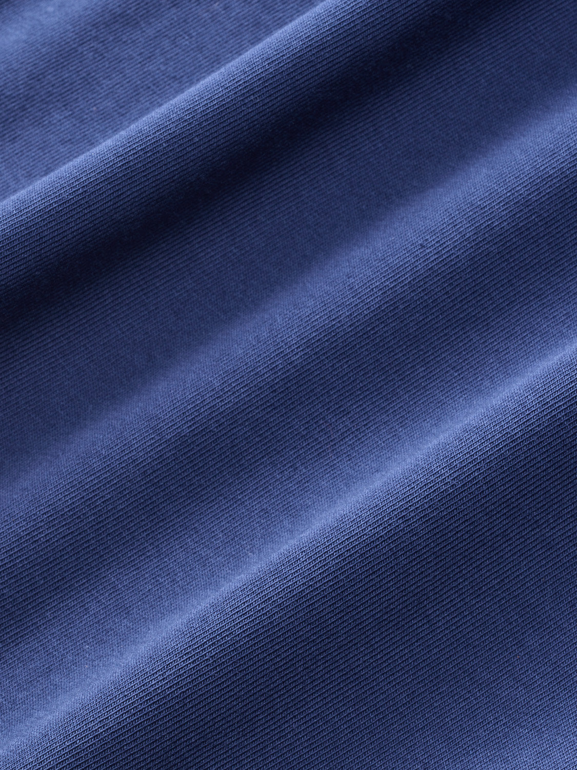 Close-up of navy blue textured fabric with ribbed weave and natural folds throughout.