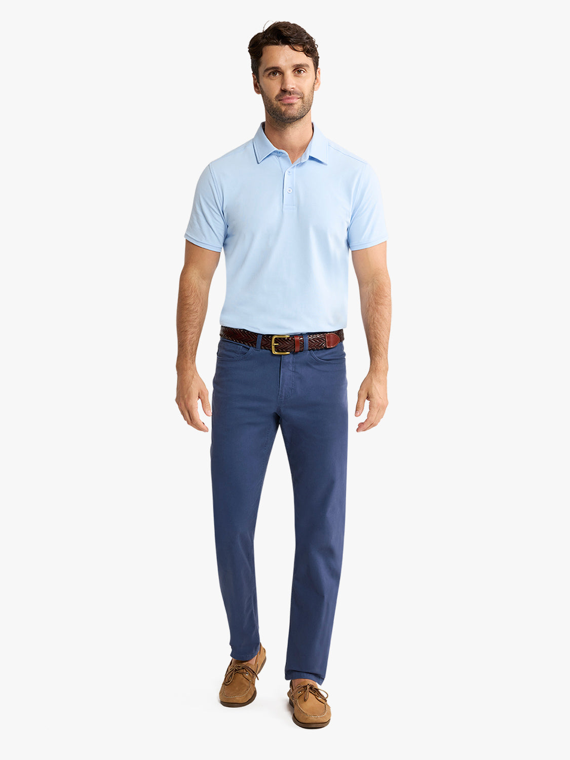 Man wearing a light blue polo shirt with short sleeves and dark navy pants with a brown belt.