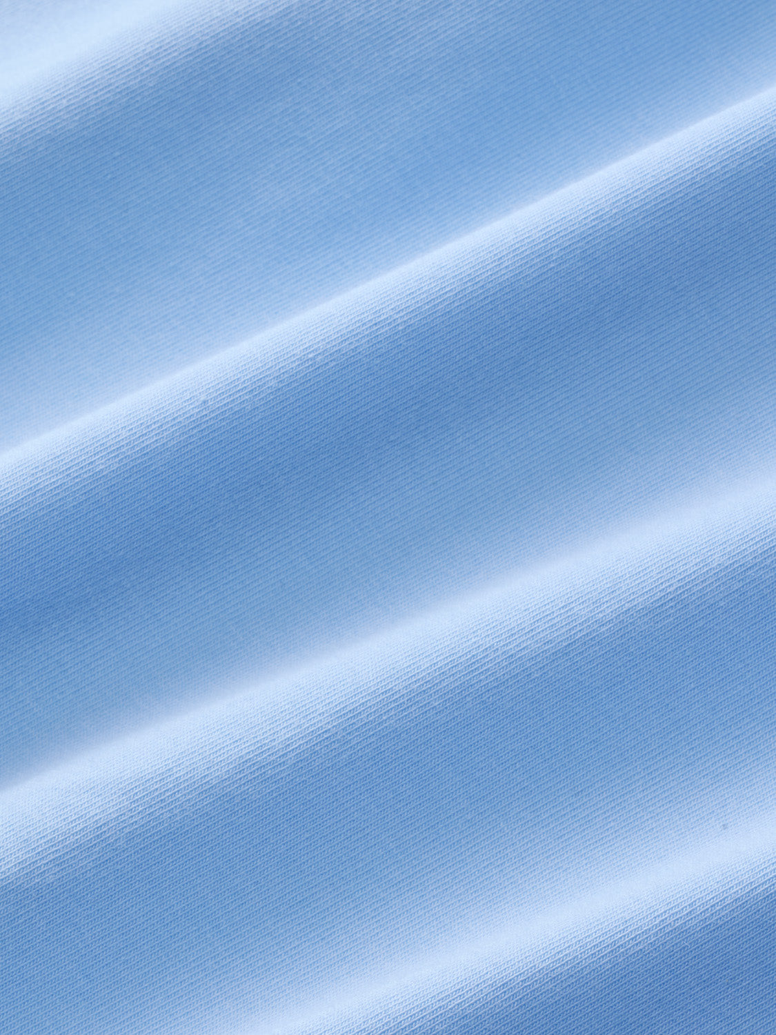 Light blue polo shirt fabric with textured weave and diagonal fold details throughout.