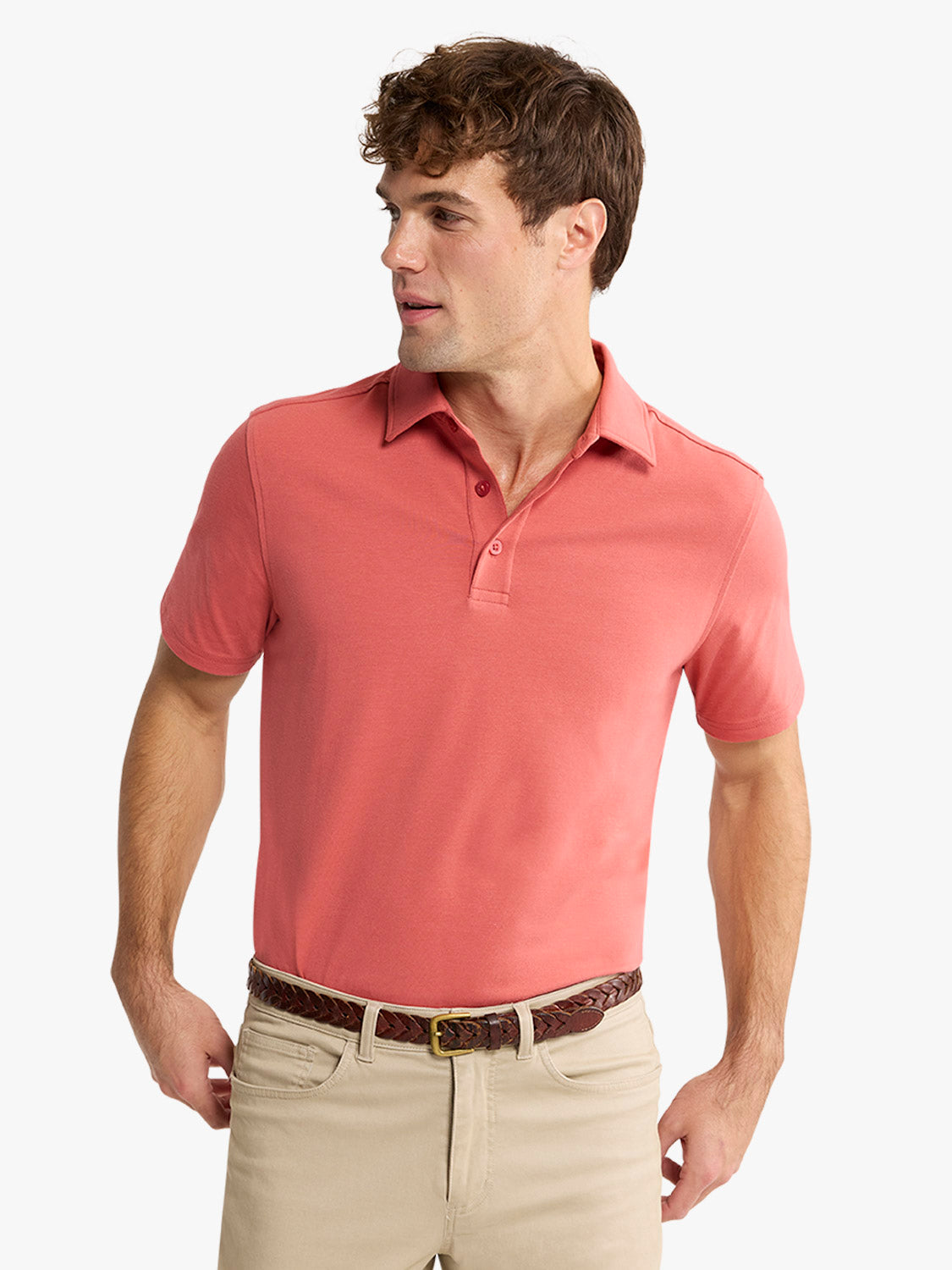 Man wearing a red polo shirt with short sleeves and a collar, paired with khaki pants and a brown belt.