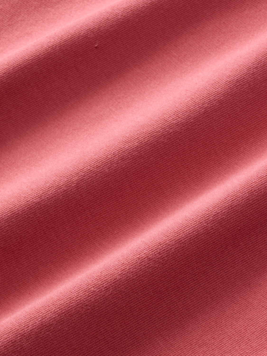 Red polo shirt fabric with ribbed texture and diagonal fold details.