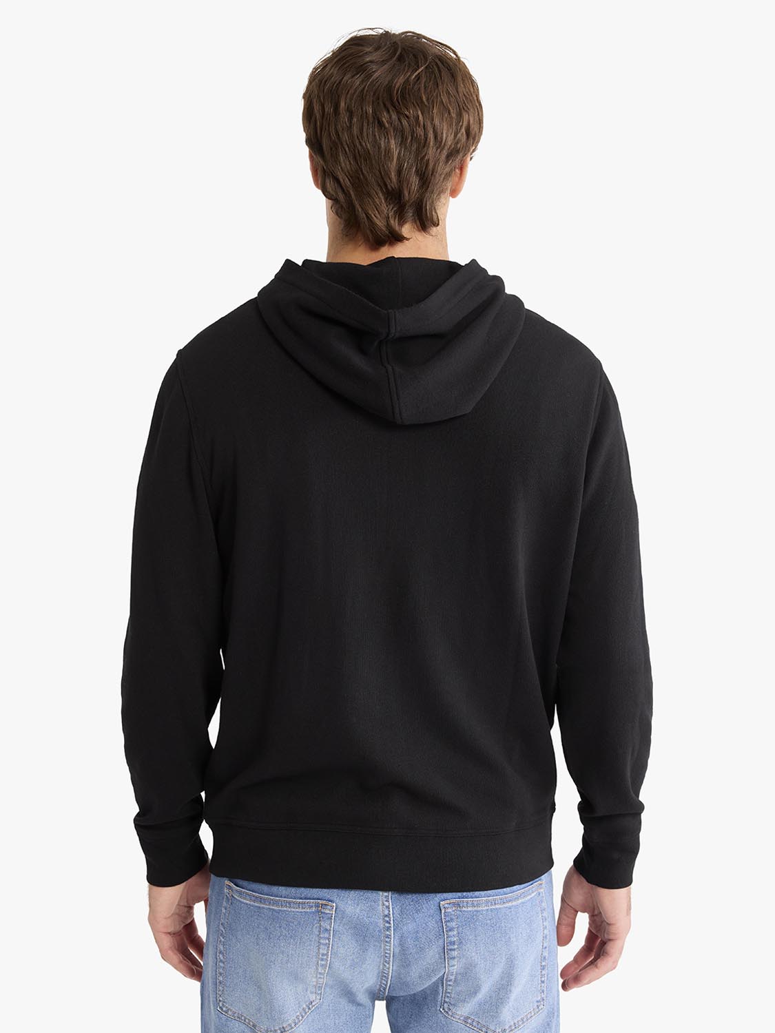Man wearing a black hooded blanket hoodie with long sleeves, shown from the back view.