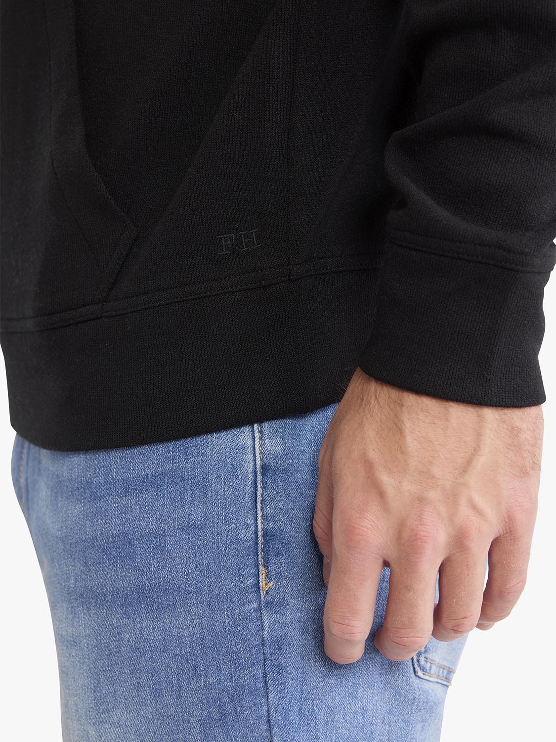 Black blanket hoodie worn with light blue jeans showing the ribbed cuff detail.
