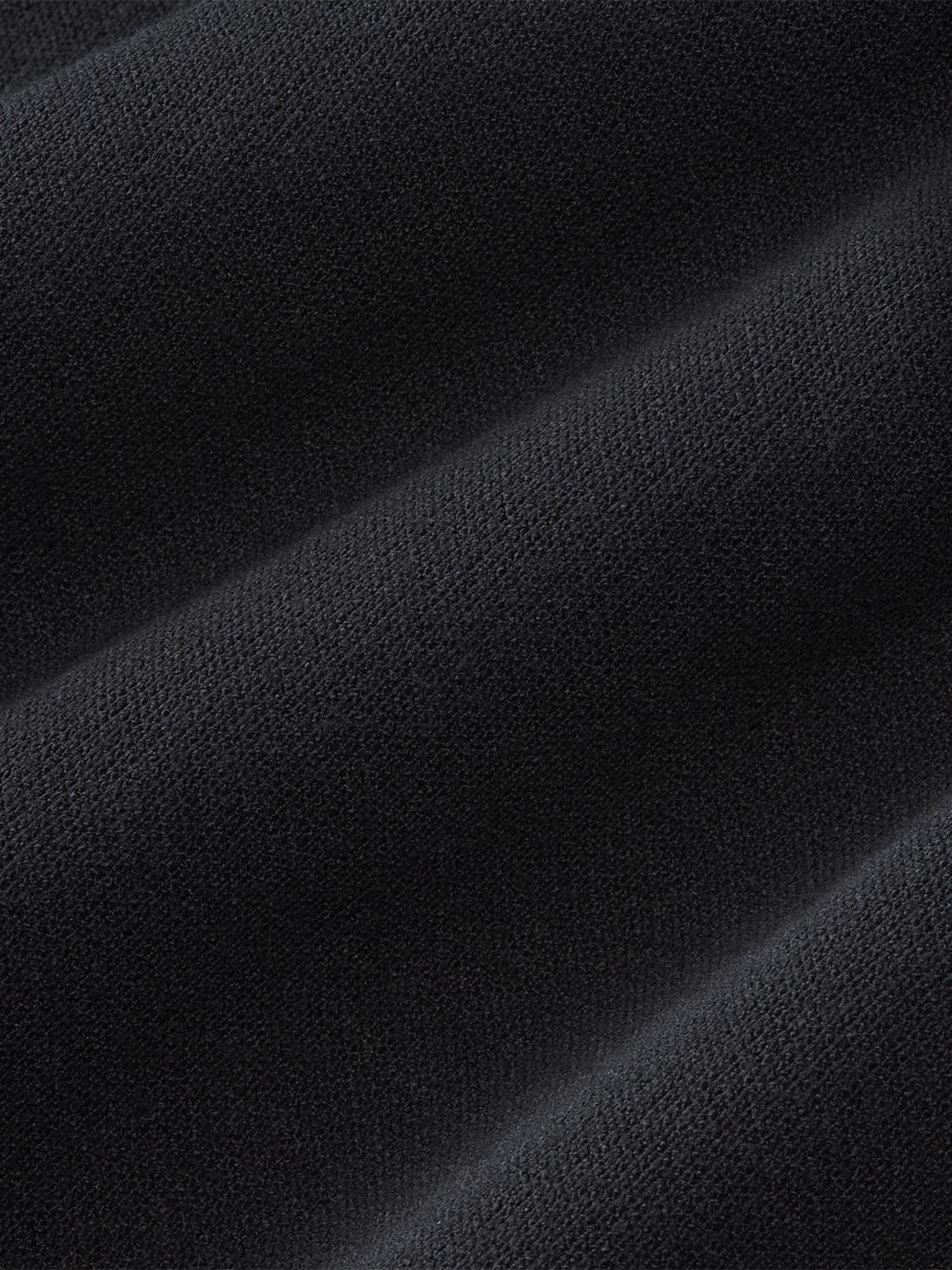 Black blanket hoodie with soft, textured fabric showing draped folds and natural light shadows.