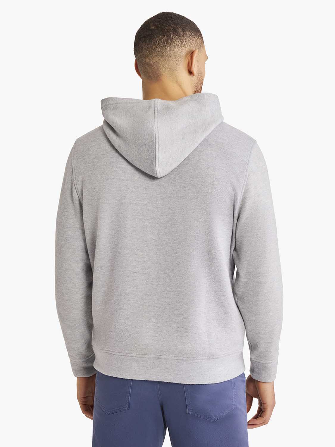 Man wearing a heather grey blanket hoodie with drawstring hood and kangaroo pocket shown from behind.