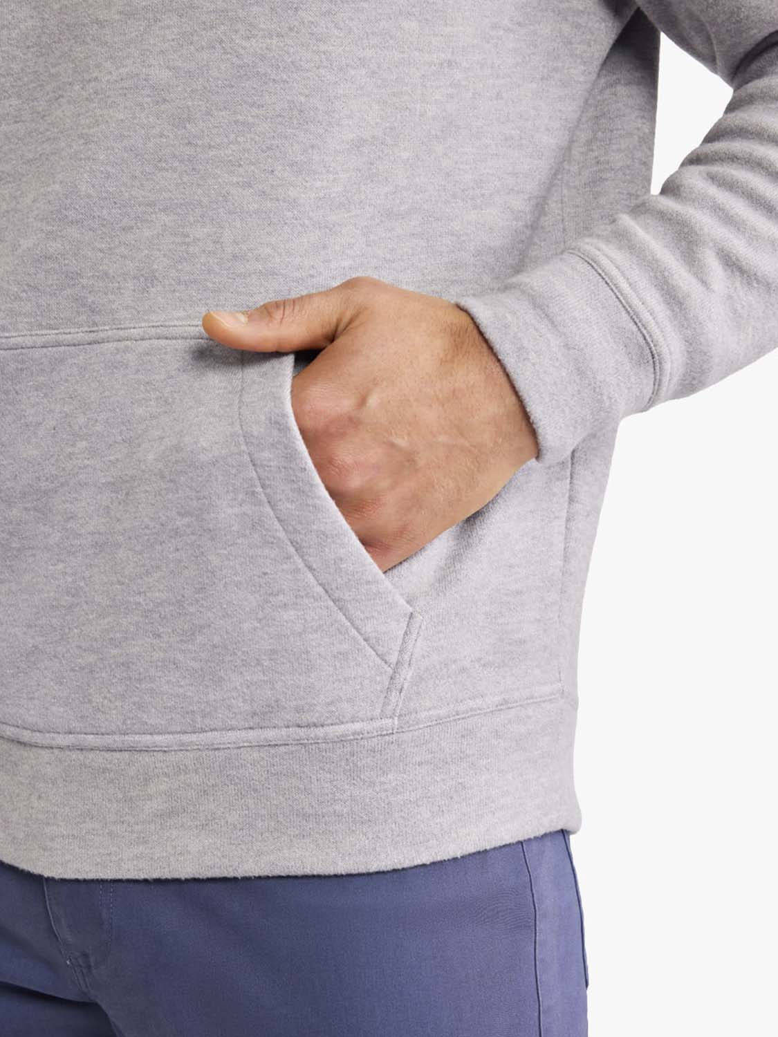 Person wearing a heather grey blanket hoodie with hand in front pocket.