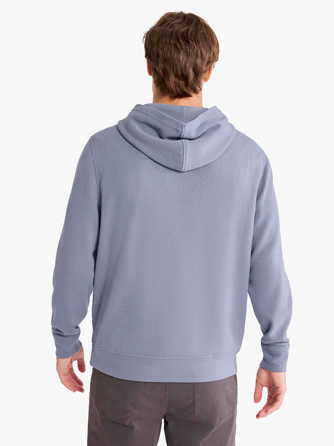 Person wearing a slate blue blanket hoodie with a hood and long sleeves over gray pants.