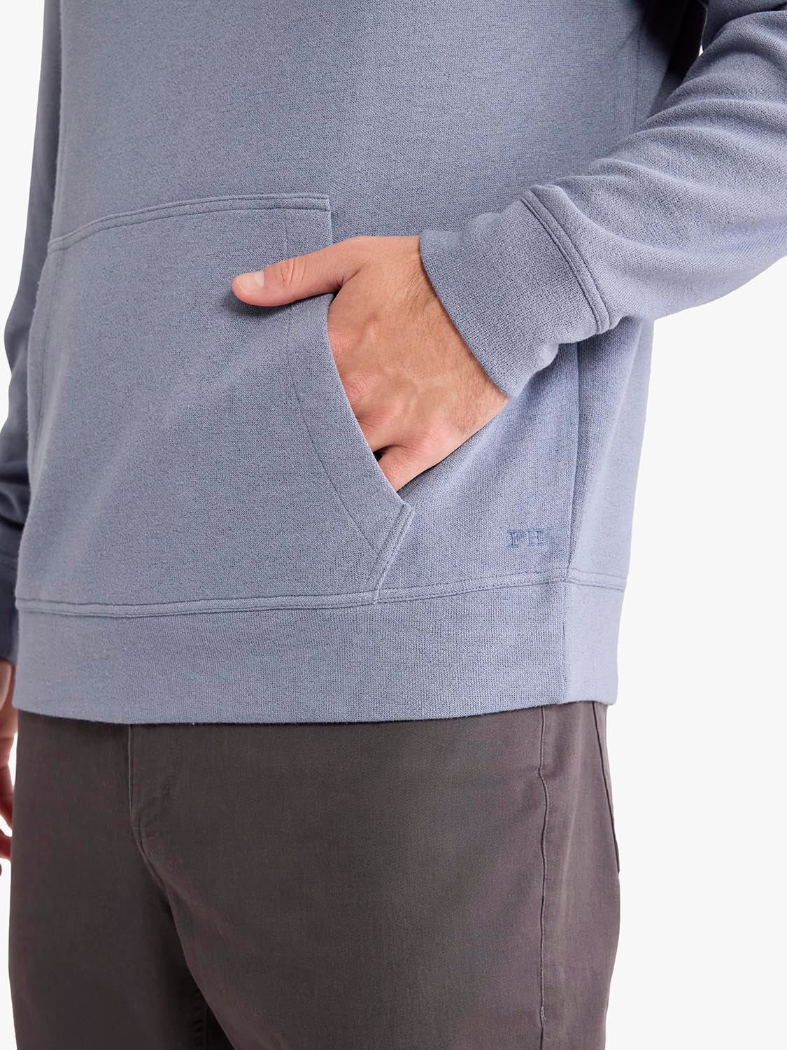 Person wearing a gray blanket hoodie with hand in front pocket and brown pants.