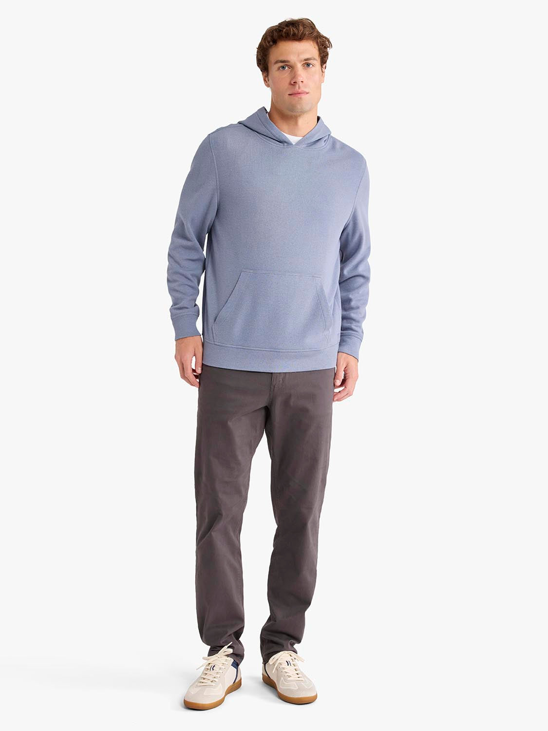 Man wearing a light blue blanket hoodie with a drawstring hood and front pocket over dark gray pants.