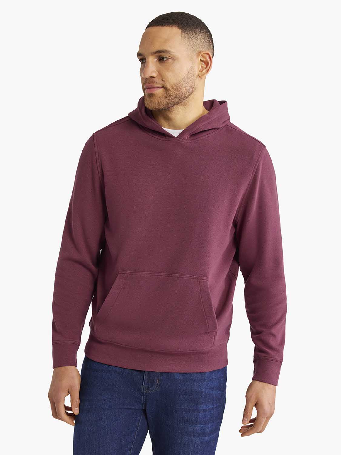 Man wearing a burgundy hoodie with a front kangaroo pocket and drawstring hood.