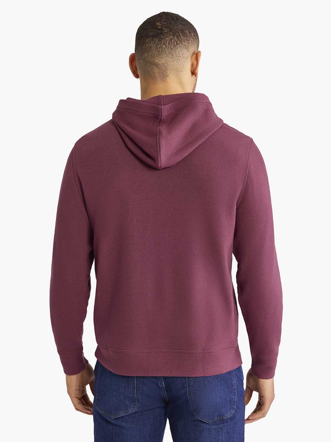Man wearing burgundy hoodie with drawstring hood viewed from back, paired with dark jeans.