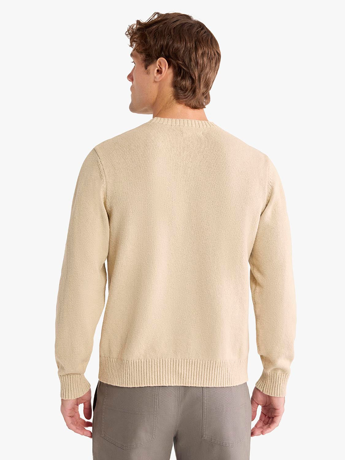 Man wearing a cream-colored crew neck sweater with ribbed cuffs and neckline, viewed from behind.