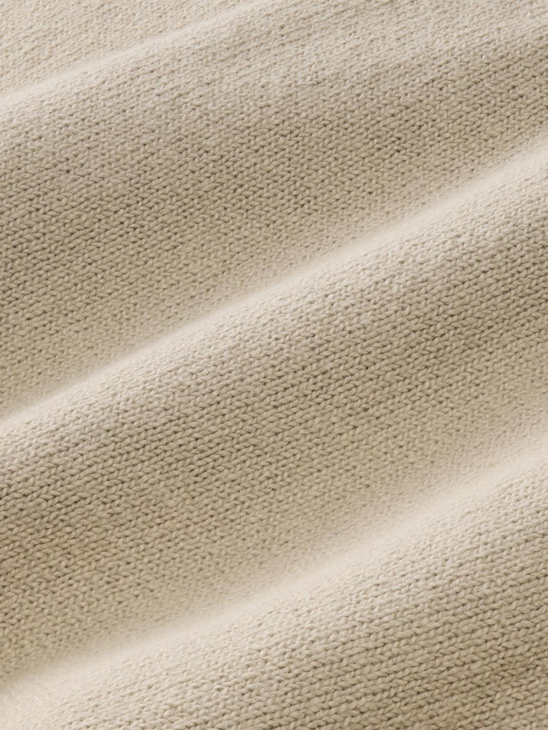 Beige crew sweater displaying textured knit fabric with diagonal folds and light shading throughout.