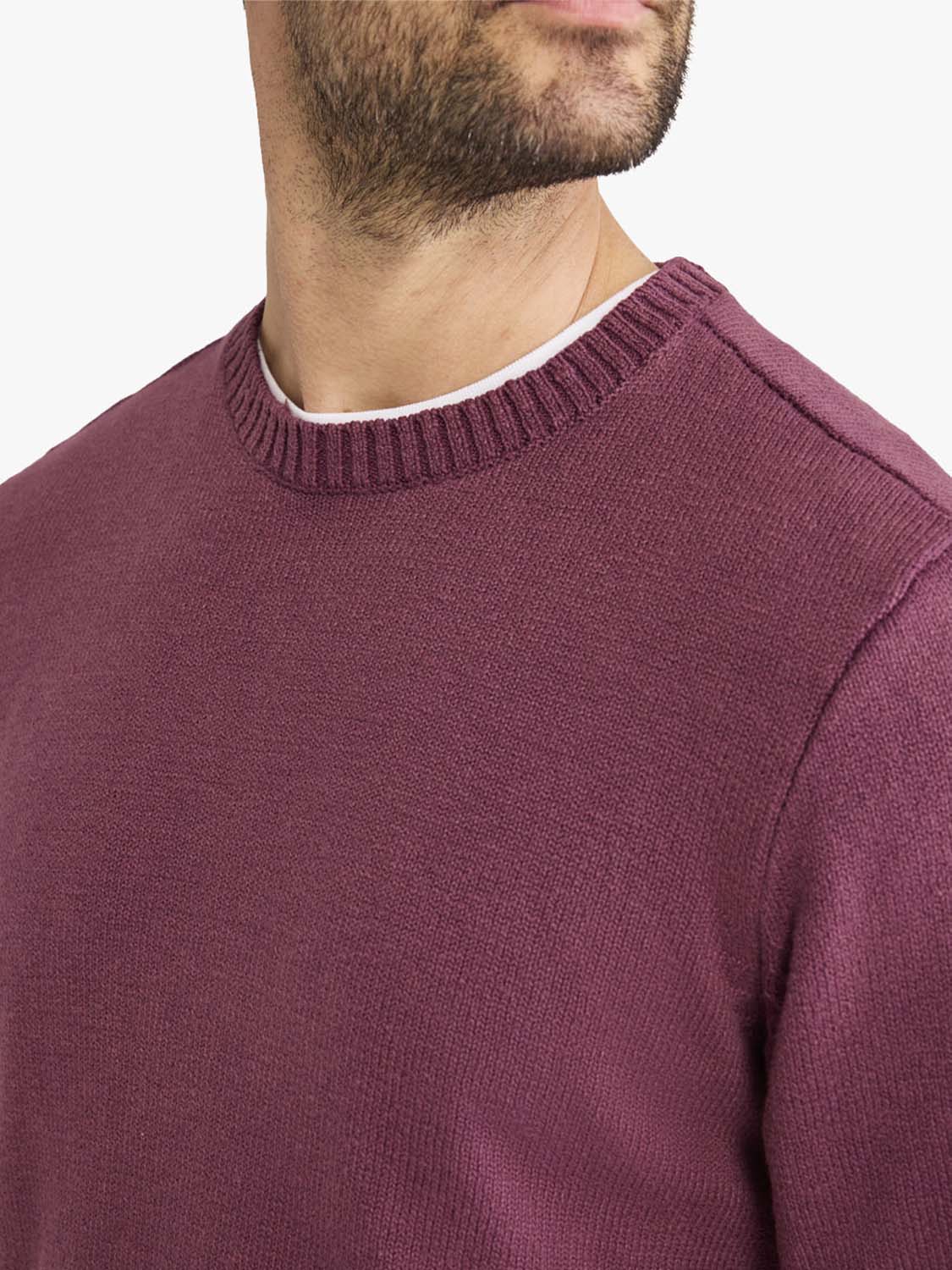 Man wearing a burgundy crew neck sweater with ribbed knit texture and white trim.